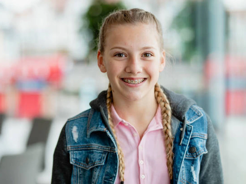 Child smiling with traditional braces, showcasing benefits and care tips for kids orthodontic treatment.