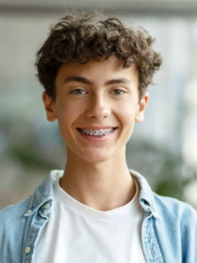 A 16 year old boy smiling while wearing traditional braces, showcasing orthodontic treatment for teenagers